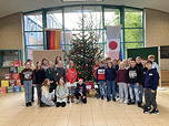 Das Foto zeigt die Schülerinnen und Schüler der Klasse 5d vor dem von ihnen geschmückten Tannenbaums im Foyer des TGG (Dezember 2023).